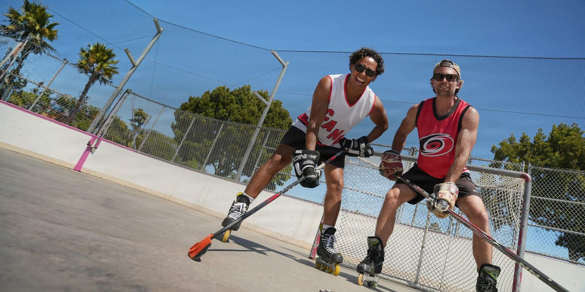 Two friends in Carolina Hurricanes hockey tanks playing roller hockey